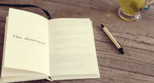 En oppslått dagbok og en blyant på et trebord.