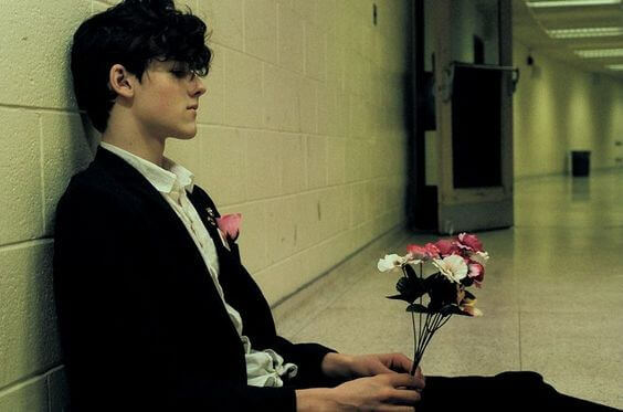 gutt som sitter i gangen med blomster som symboliserer å forlate partneren din, men ikke kunne