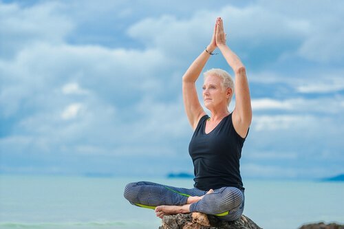 Midorexia - en eldre kvinne sitter på en bergknaus og gjøre yoga.