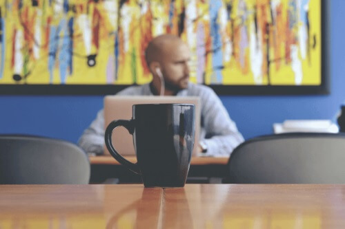 En fyr på en kaffebar som jobber på sin datamaskin