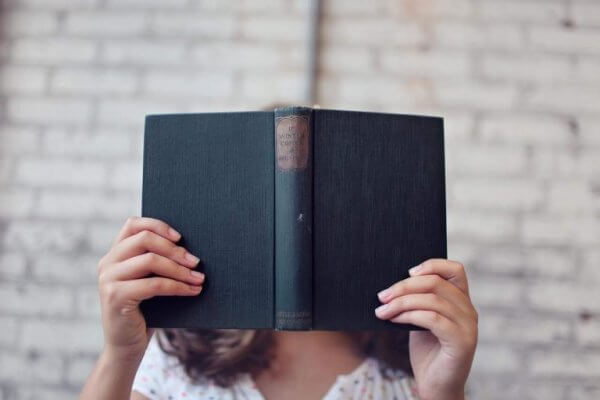 Kvinne som dekker ansiktet sitt med en bok