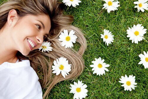 En kvinne som ligger ved siden av blomster og smiler