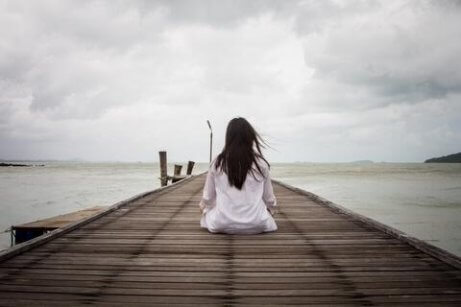 kvinne sitter foran havet