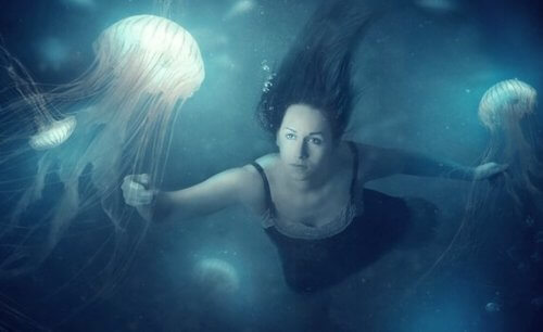 Kvinne under vann med maneter