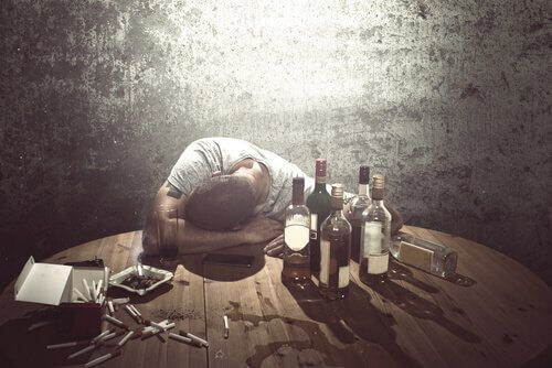 En mann med alkoholforstyrrelser omgitt av flasker av alkohol
