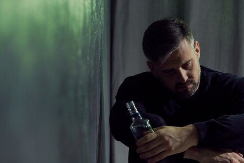 En trist mann som holder en flaske alkohol