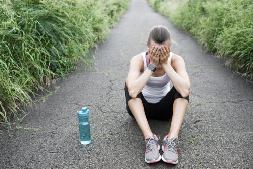 En utmattet løper med overtreningssyndrom sitter på bakken.