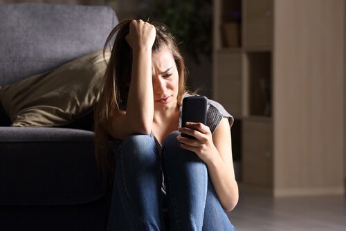 Jente med FOMO syndrom stirrer på smarttelefonen.