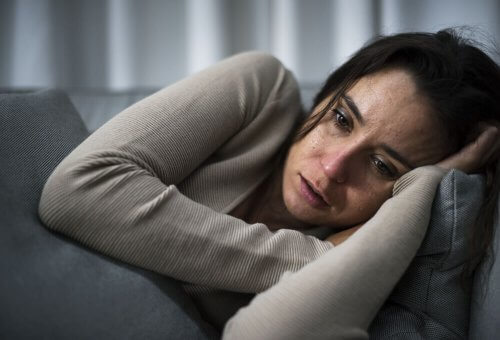 Kvinne med kognitivt oppmerksomhetssyndrom som gråter på sofaen.