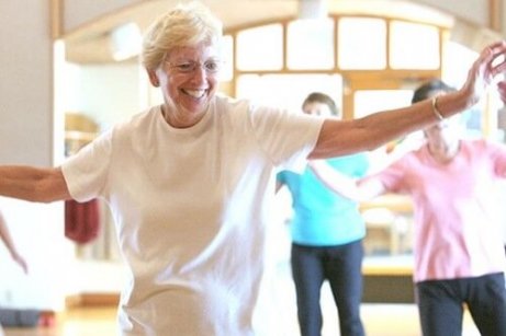 En eldre kvinne danser med et smil i ansiktet