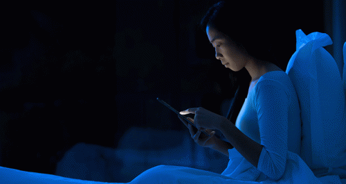 Kvinne i sengen med mobiltelefon