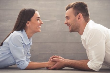 En mann og kvinne holder hender og snakker til hverandre, smiler