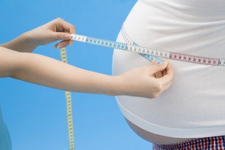 En person som måler en annen persons overvektige mage
