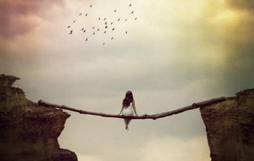 En kvinne som sitter på tømmer over en kløft.