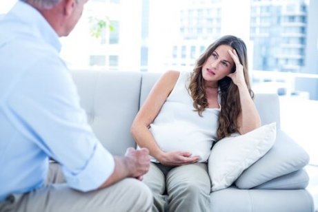 En stresset gravid kvinne som sitter i sofaen