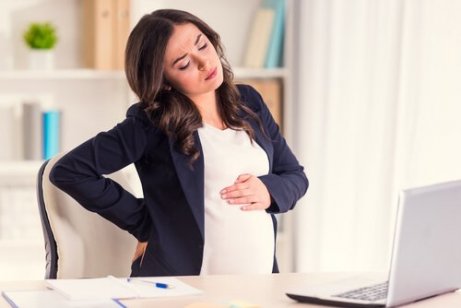 En stresset gravid kvinne på kontoret sitt