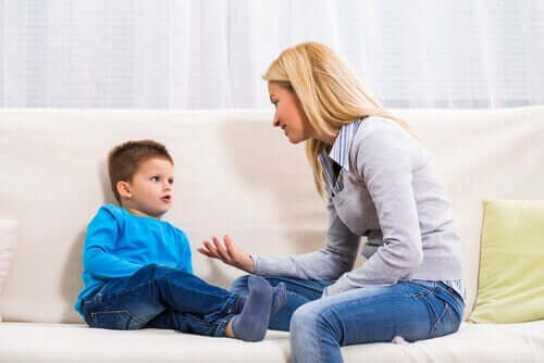 En mamma som sitter i sofaen sammen med sønnen sin og forklarte ham noe.
