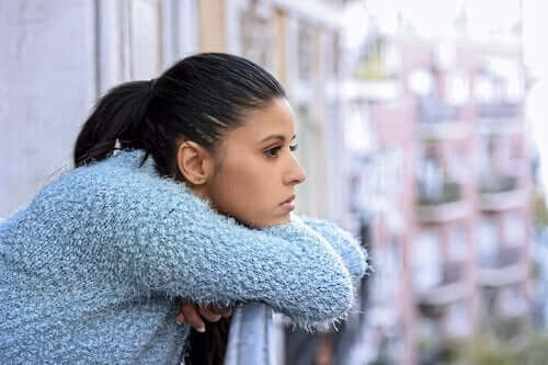 En kvinne som lener seg på balkongen sin i dype tanker.