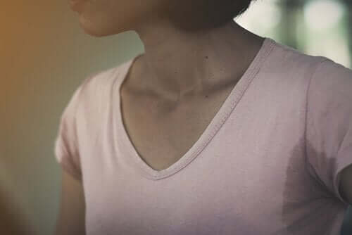 Et bilde som viser en kvinne med hyperhidrose i en skjorte med store svette armhuleflekker.