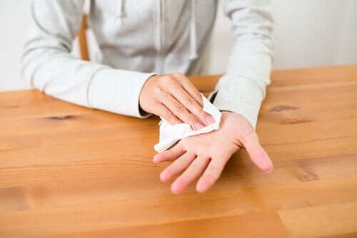 En person som tørker den svette hånden sin med et serviett.