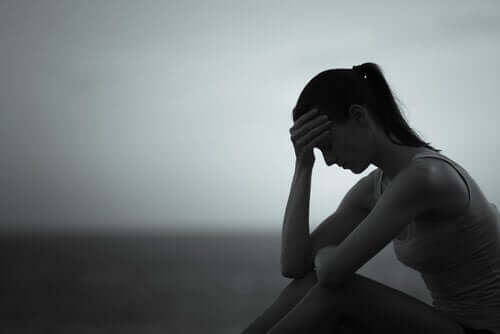 Svart og hvitt bilde av en kvinne som sitter med hodet i hendene