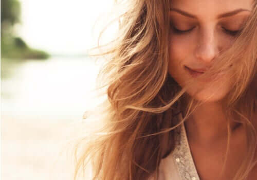 Kvinne som smiler med øynene lukket