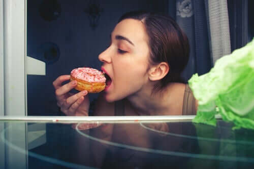 Kvinne som spiser en rosa donut
