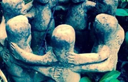 Små stenstatuer av menn står i en ring med armene rundt hverandre