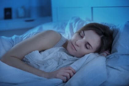 Kvinne som sover godt i sengen sin