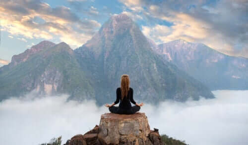 En person som mediterer på toppen av et fjell for å takle sin mentale tretthet.