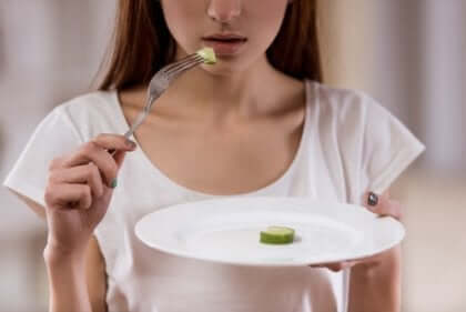 En kvinne med spiseforstyrrelser spiser en skive agurk