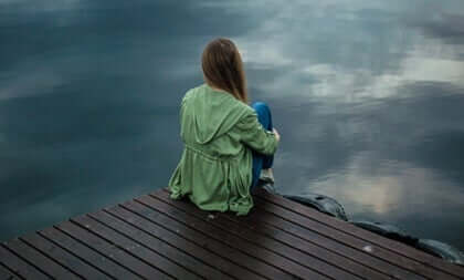 En kvinne på en brygge foran havet.