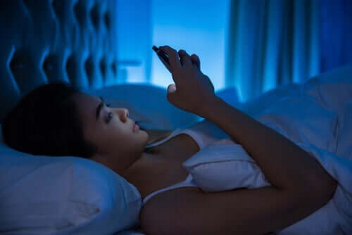 En kvinne som sender sms i sengen.