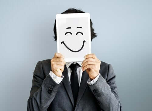 En mann som holder et lykkelig ansikt tegnet på et papir.