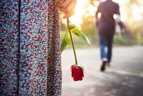 En mann som går fra en kvinne som holder en rose