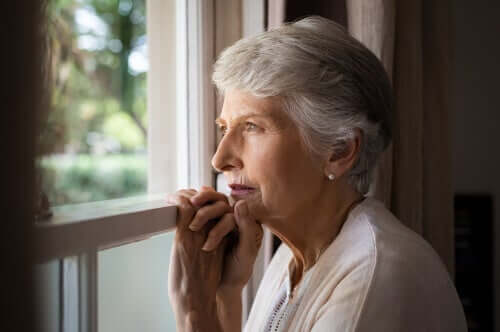 En eldre kvinne som ser ut av vinduet.