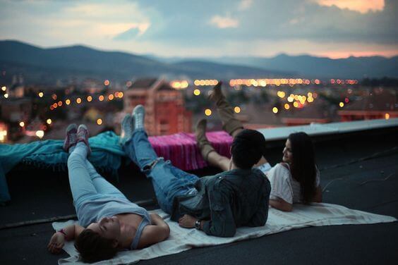 Venner ligger på en takterrasse og ser på solnedgangen.