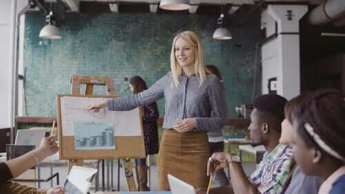 En kvinne som holder en presentasjon for en liten gruppe mennesker i en romslig bygning.