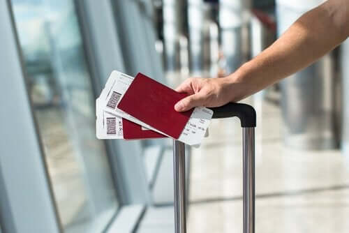 En person som går gjennom en flyplass med en koffert og to pass i hånden.