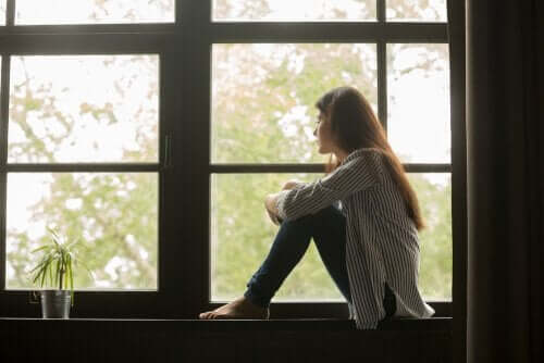 En trist kvinne som ser ut av vinduet og vurderer livet sitt.