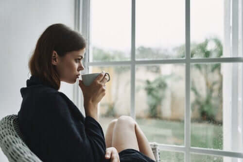 En kvinne drikker kaffe ved vinduet