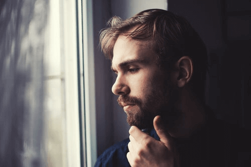 En mann sitter ved vinduet og tenker