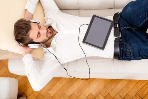 En mann ligger og lytter til musikk