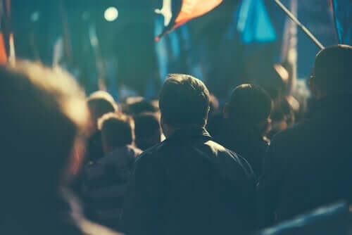 Ryggen til en mann som går i et demonstrasjonståg.