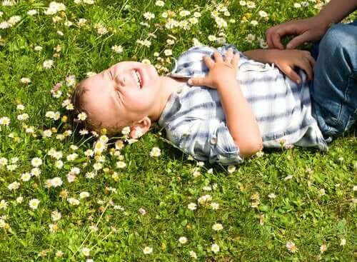 En gutt som ligger i en blomstereng som ler.