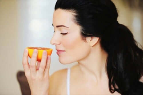 En kvinne som lukter på en appelsin.