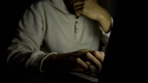 En mann som sitter med PCen i mørket