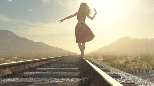 En kvinne som balanserer på en jernbane.