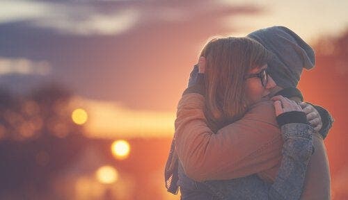 To mennesker som klemmer hverandre forran en vakker solnedgang er et fint bilde på emosjonelle uttrykk.
