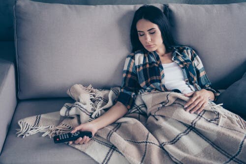 En kvinne som sover på sofaen.